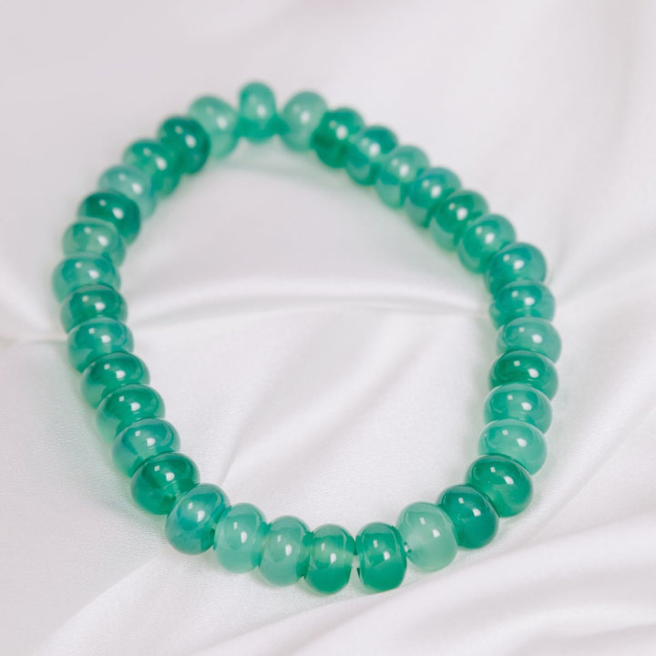 a green onyx button bracelet on a white cloth