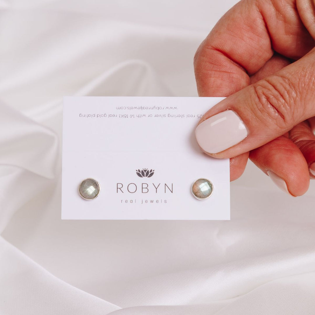 a woman holding a card with earrings in her hand