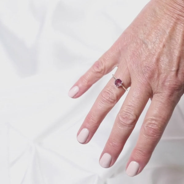a woman wearing a gemstone ring on her finger