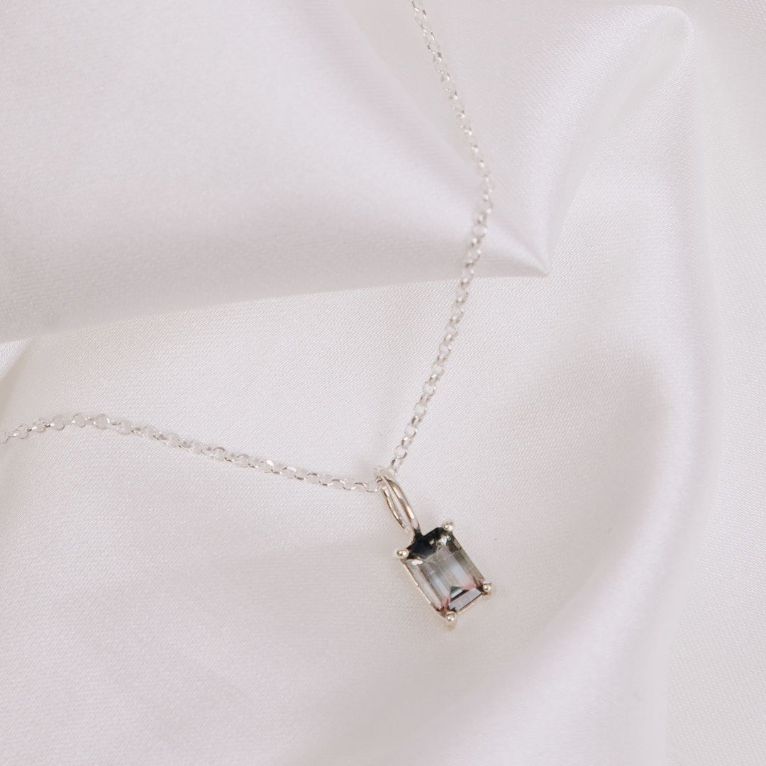 a pendant necklace on a white cloth