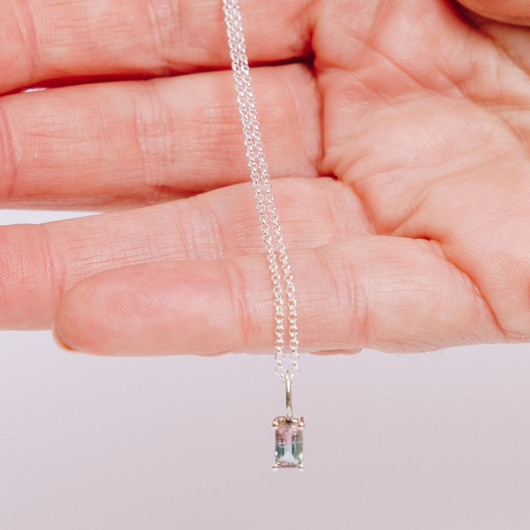 a woman holding a pendant necklace in her hand