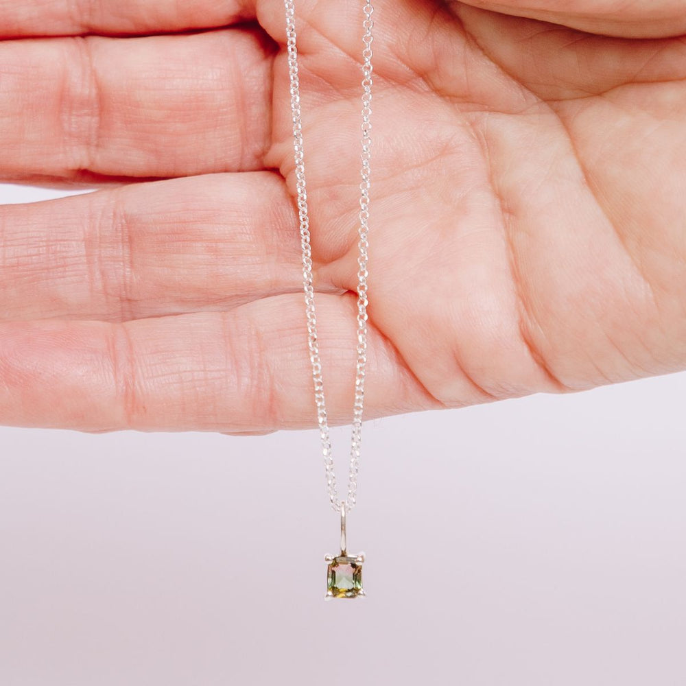 a woman holding a pendant necklace in her hand