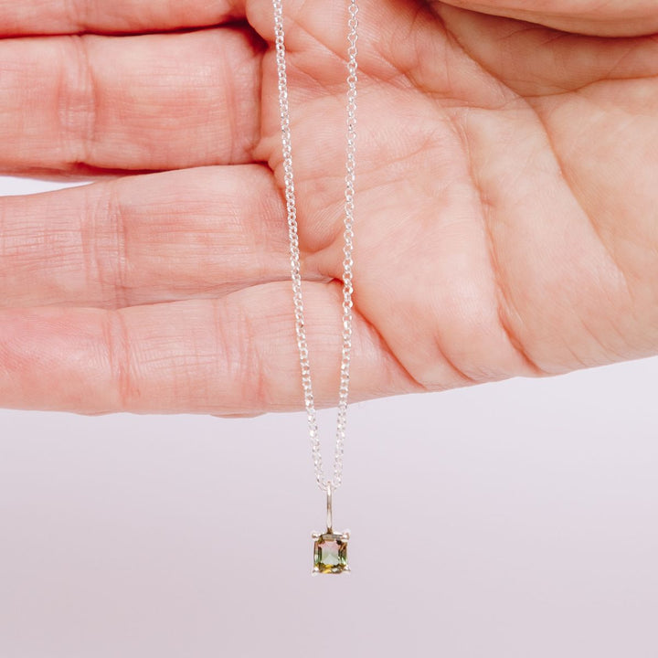 a woman holding a pendant necklace in her hand