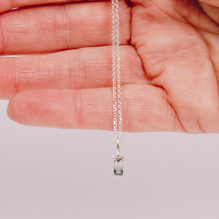 a woman holding a pendant necklace in her hand