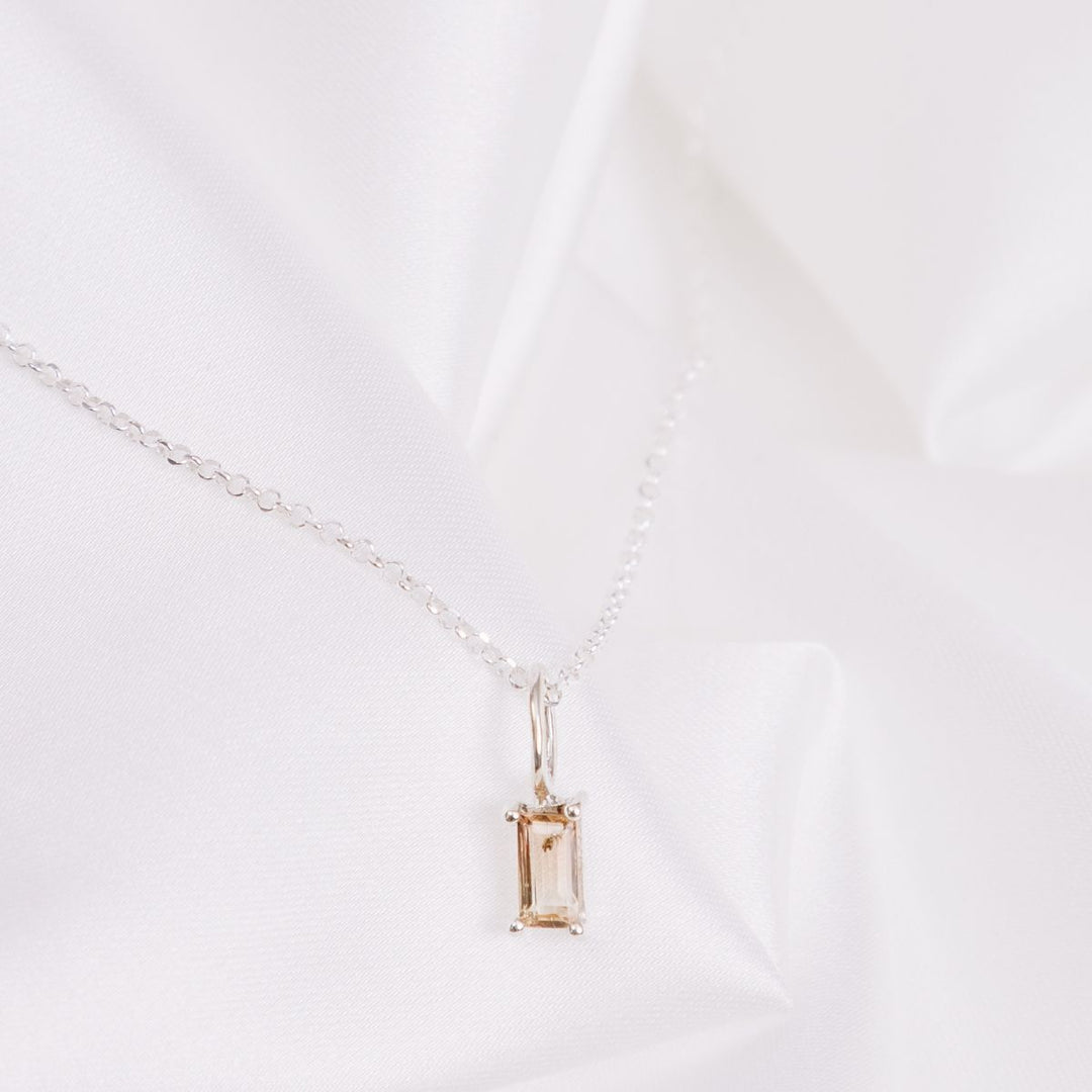 a pendant necklace on a white cloth