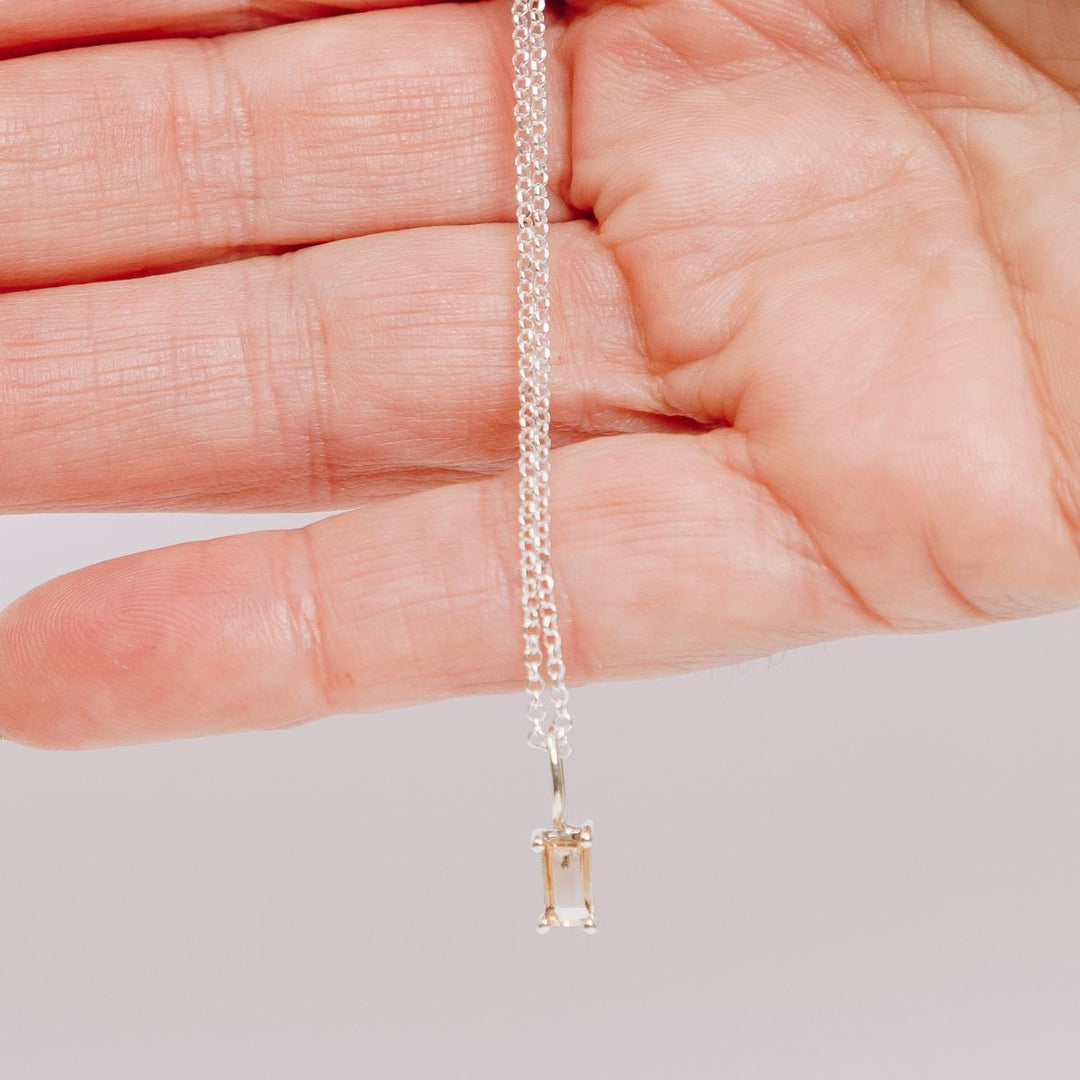 a woman holding a pendant necklace in her hand