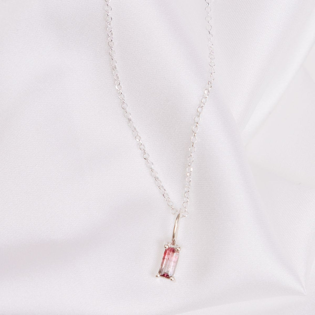 a pendant necklace on a white cloth