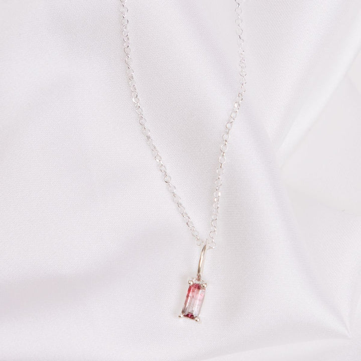 a pendant necklace on a white cloth