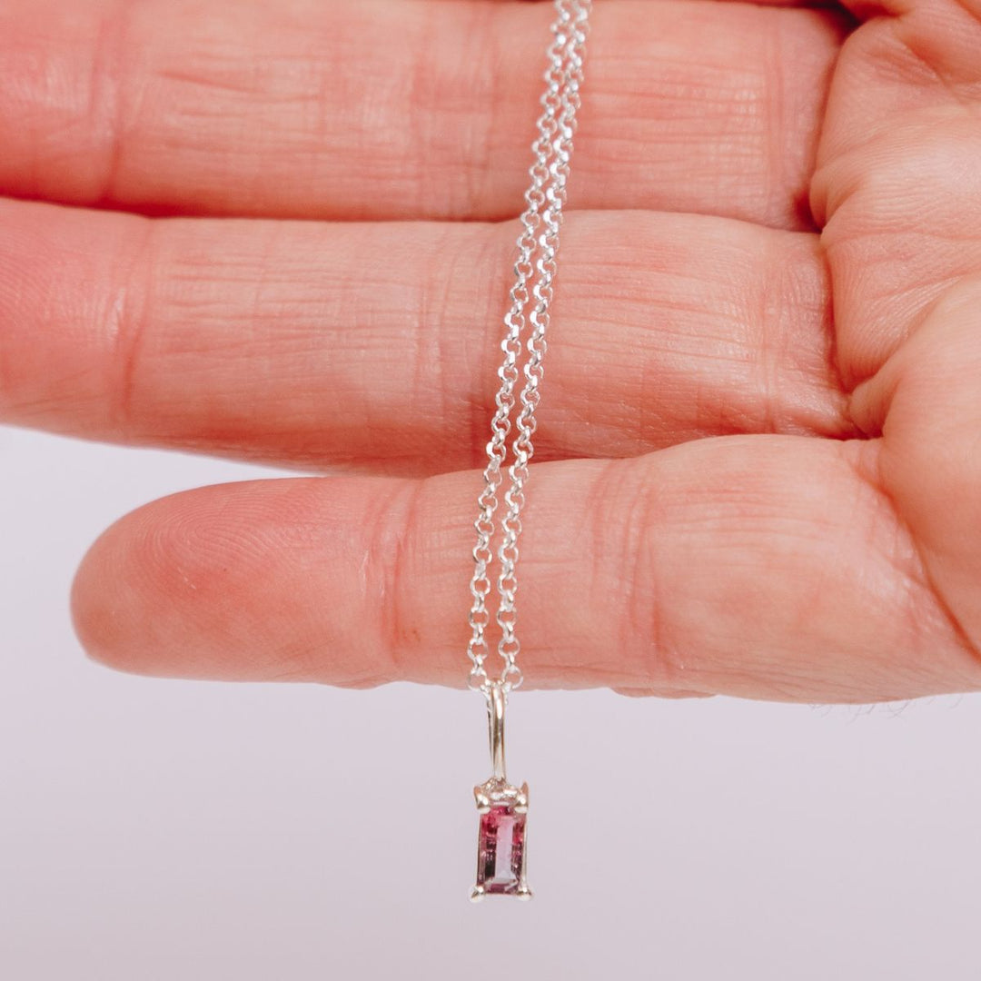 a woman holding a pendant necklace in her hand
