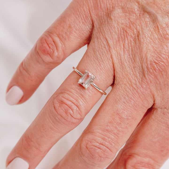 a woman wearing a gemstone ring on her finger