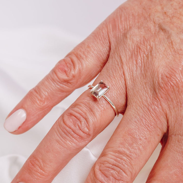 a woman wearing a gemstone ring on her finger