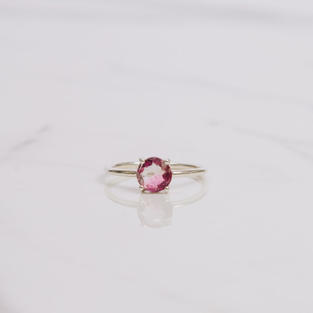 a pink gemstone ring on a white background