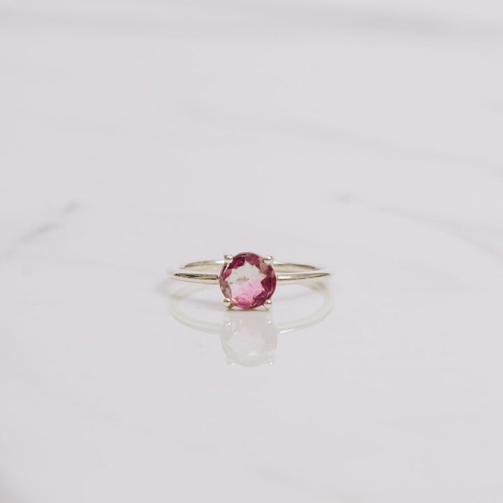 a pink gemstone ring on a white background
