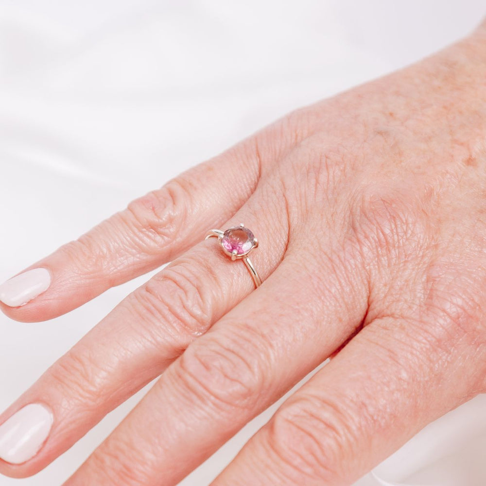 a woman wearing a pink gemstone ring on her finger
