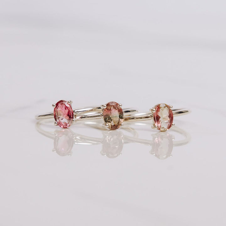 three oval shaped gemstone rings on a white background