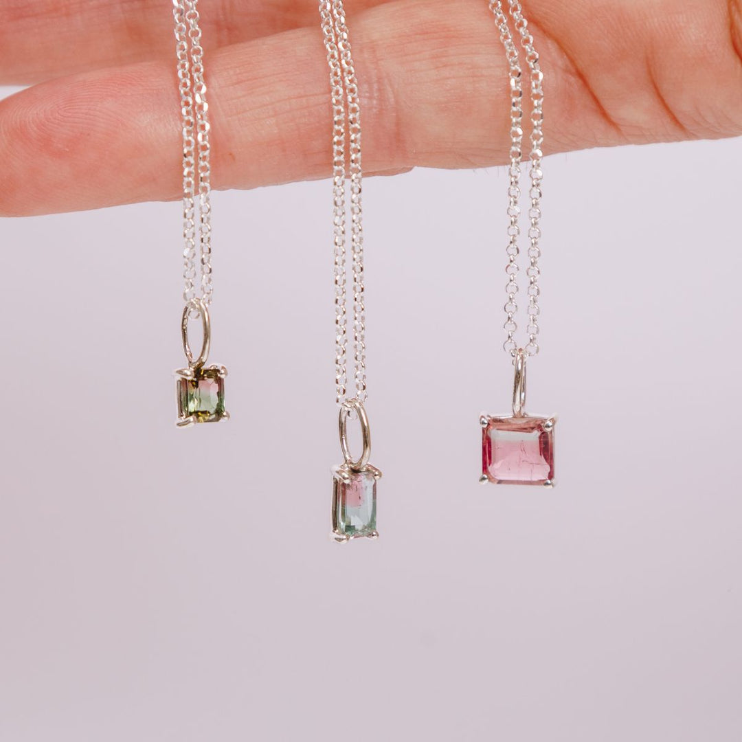 a woman holding three pendants in her hand