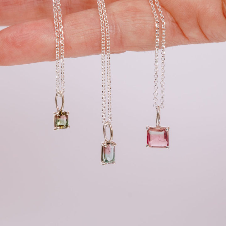 a woman holding three pendants in her hand