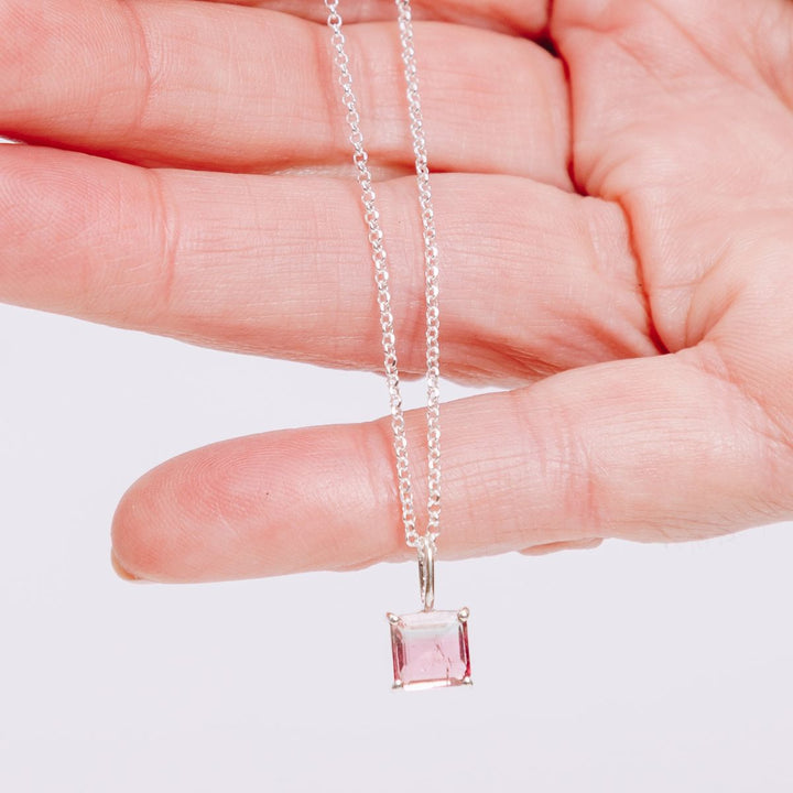 a woman holding a pendant necklace in her hand