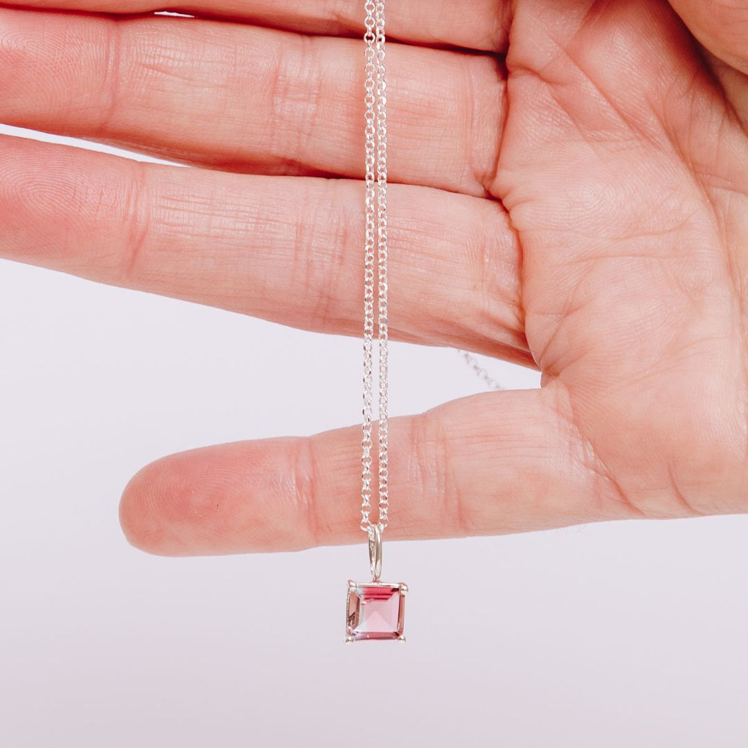 a woman holding a pendant necklace in her hand
