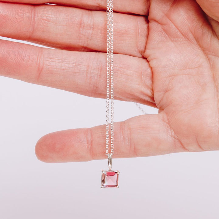 a woman holding a pendant necklace in her hand