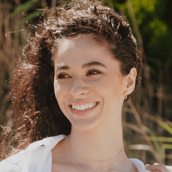 model smiling with necklaces on her neck and rectangle hoops in her ears