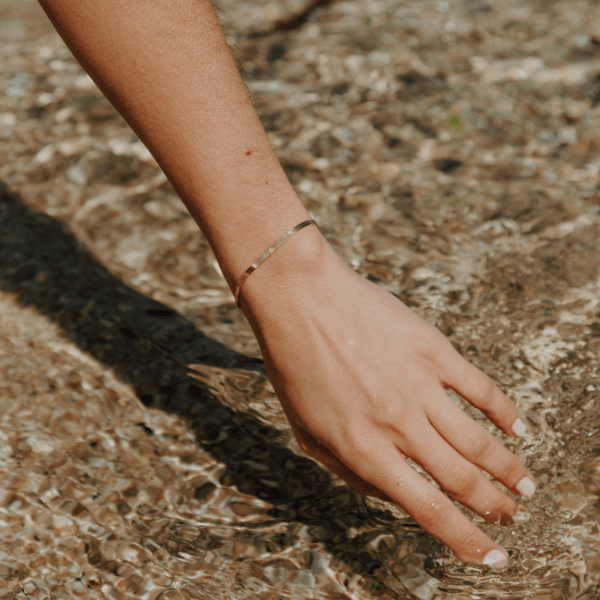 waterproof herringbone bracelet on models hand over the water 