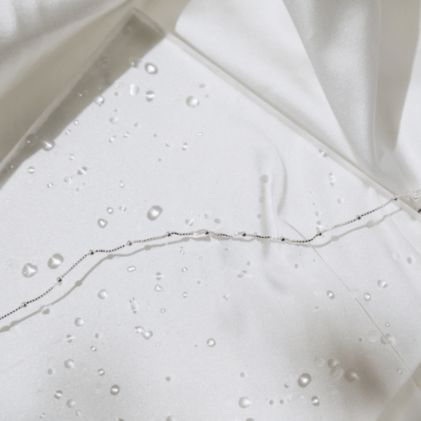 Waterproof Modern Dotted Necklace on clear slab with water droplet on a white sheet