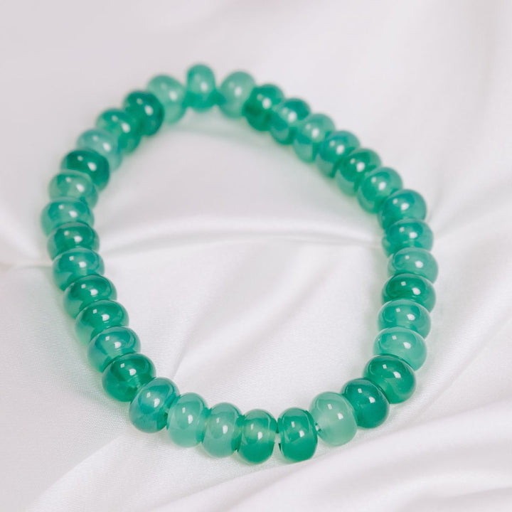 a green onyx button bracelet on a white cloth 