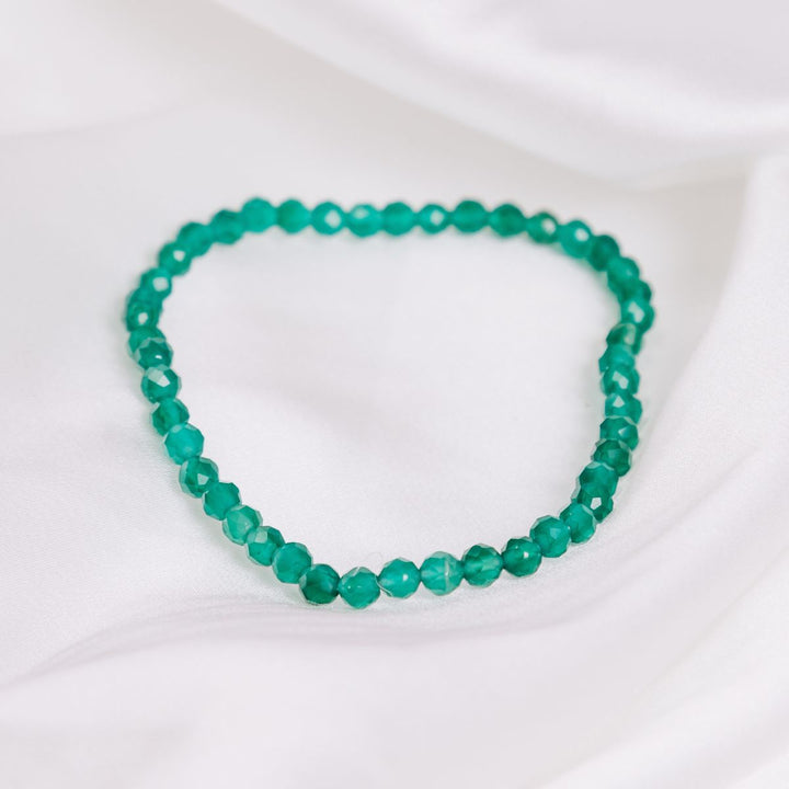 a green facetted stone bracelet on a white cloth