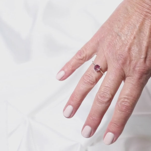 a woman wearing a gemstone ring on her finger 