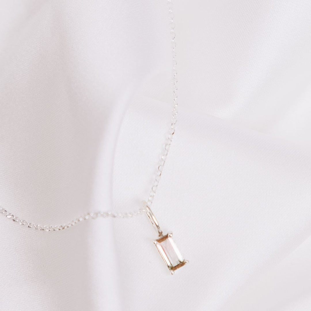 a pendant necklace on a white cloth