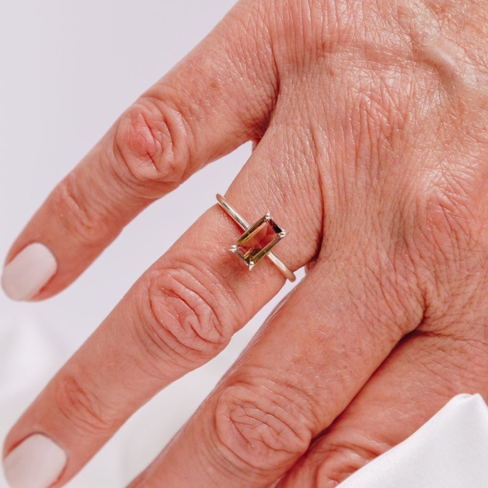 a woman wearing a gemstone ring on her finger 
