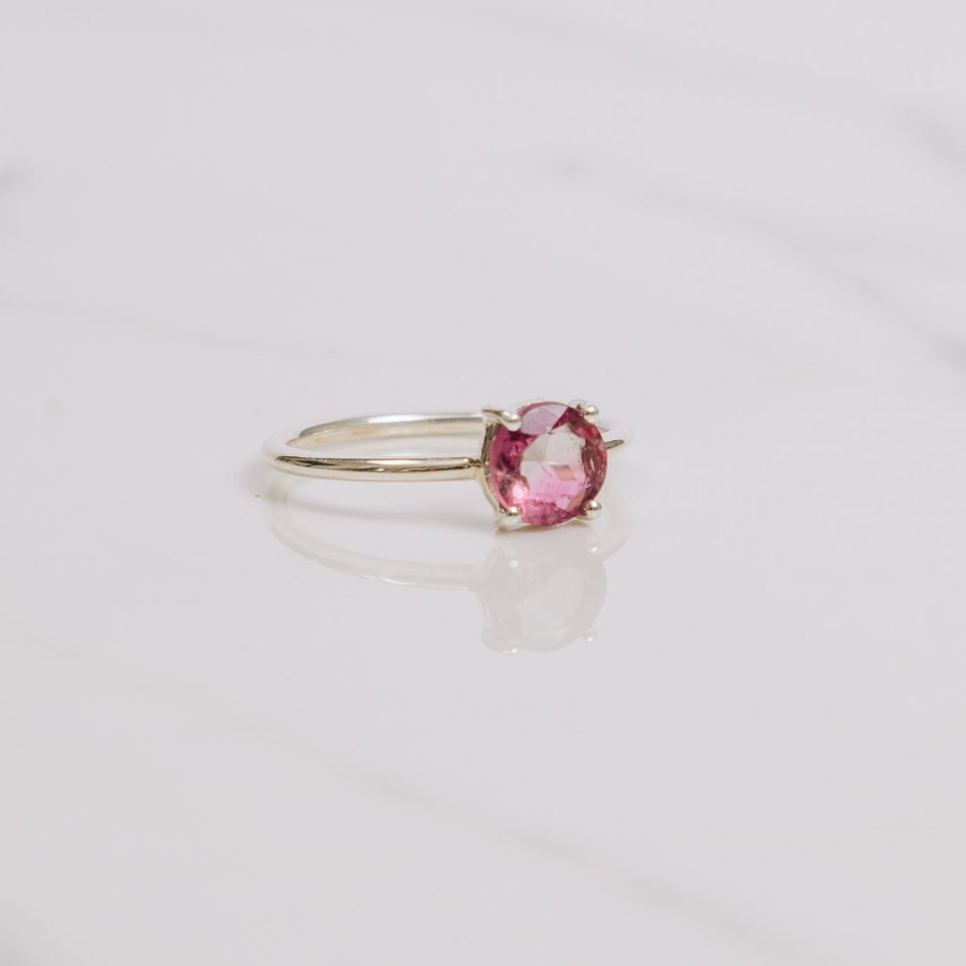 a pink gemstone ring on a white background