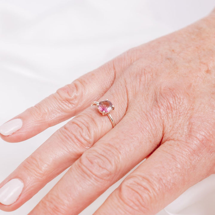 a woman wearing a pink gemstone ring on her finger 