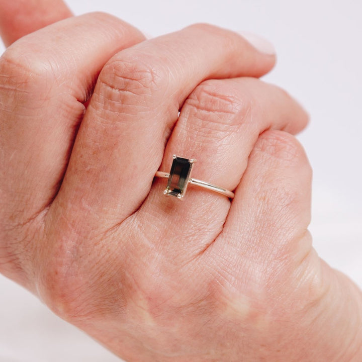a woman wearing a very bold rectangular shaped ring on her finger 
